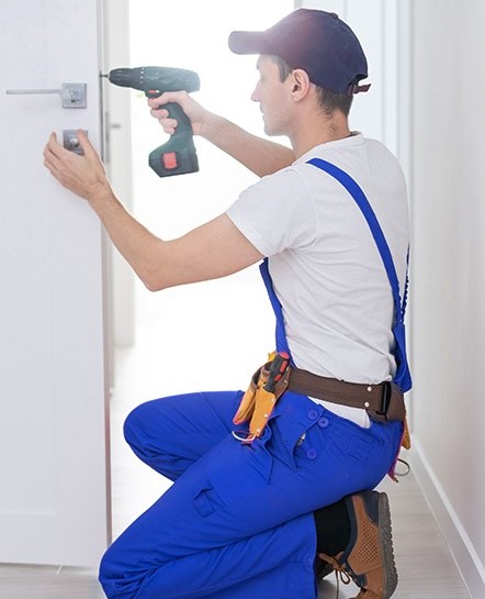 man using hand drill on door